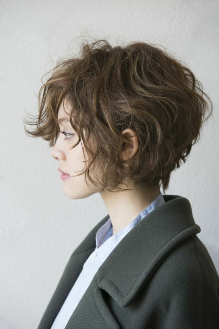 cute hairstyles, young woman facing to one side, with messy curly brown hair, wearing black woolen coat and blue shirt