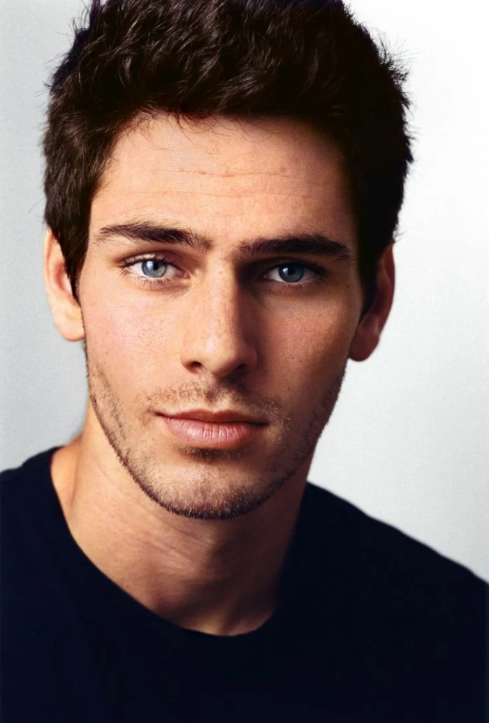 dark blue eyes, close up of a smiling young man with short dark wavy hair, with stubble and black t-shirt