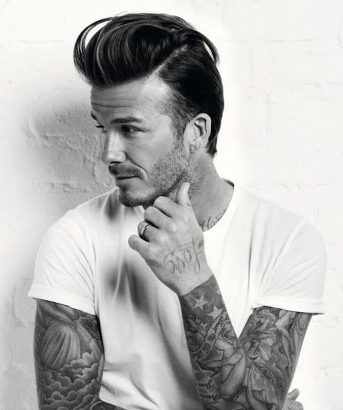 David Beckham wearing white t-shirt, with arm tattoos and stubble beard, hair with undercut and pompadour