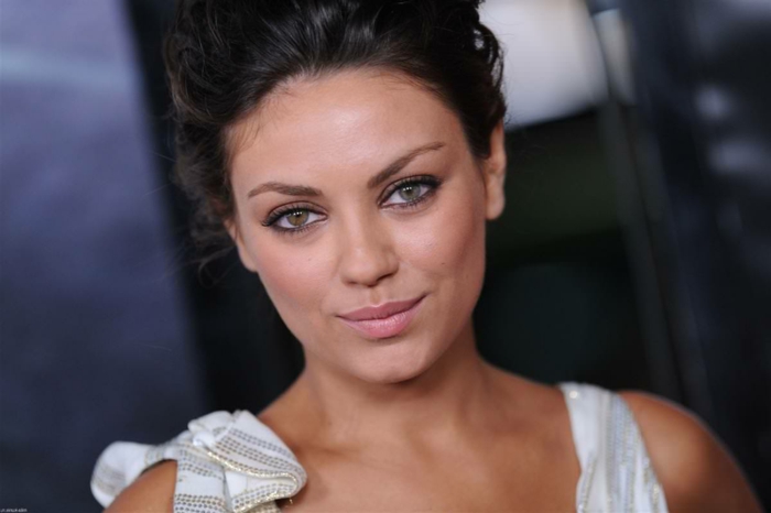 different colored eyes, mila kunis with dark hair tied up and white top, one of her eyes is hazel, while the other is blue