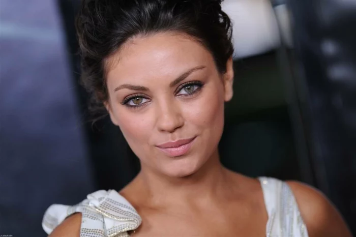 different colored eyes, mila kunis with dark hair tied up and white top, one of her eyes is hazel, while the other is blue