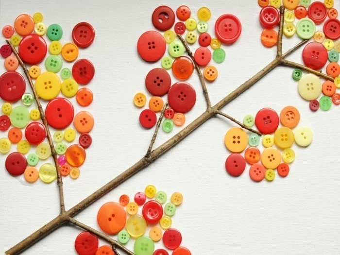 cool things to make at home, collage made from a twig stuck on white paper, decorated with multicolored buttons in different sizes, looking like autumn leaves