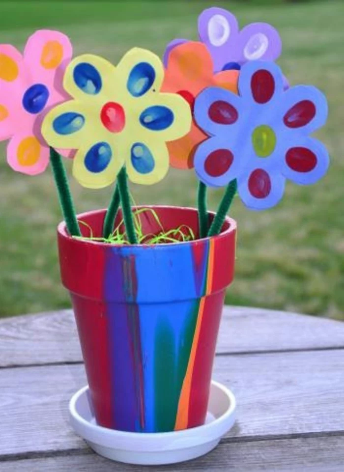 hand-painted clay flower pot, containing five paper flowers in different colors, decorated with finger prints, and attached to green fuzzy wire