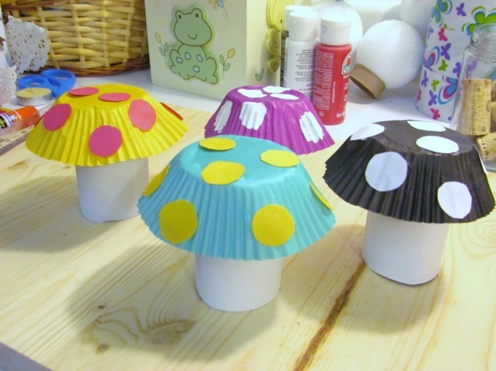 cool things to make at home, four mushrooms made from white paper, and muffin moulds in different colors, decorated with pink white and yellow paper dots