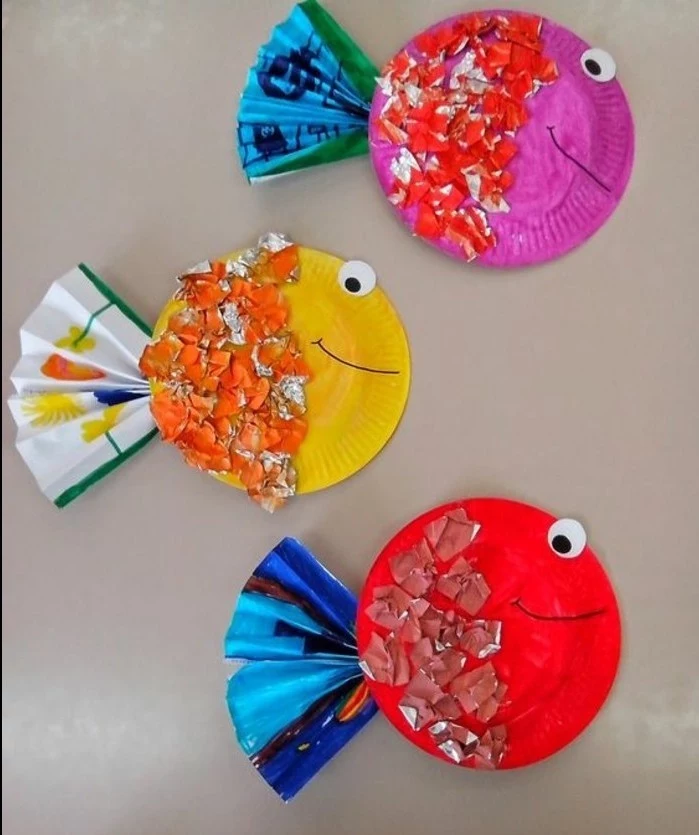 fun art projects, three paper plates painted to look like fish, decorated with paper shreds and folded paper details