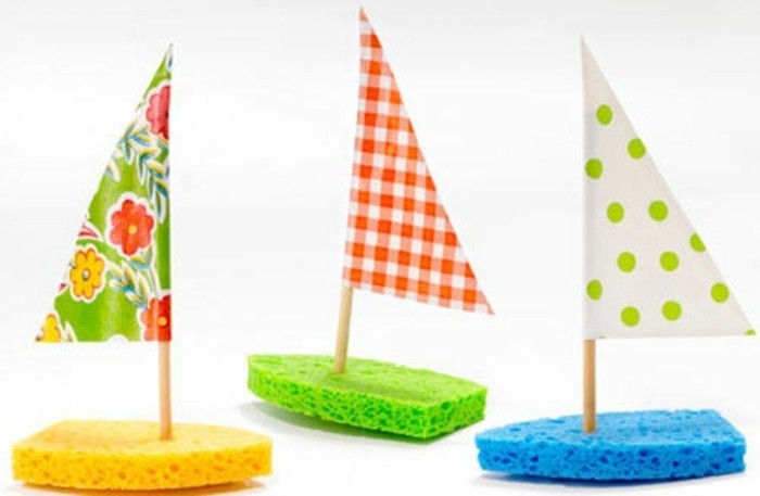fun art projects, three boats made from sponges in yellow, green and blue, decorated with triangular sails made from colorful crepe paper