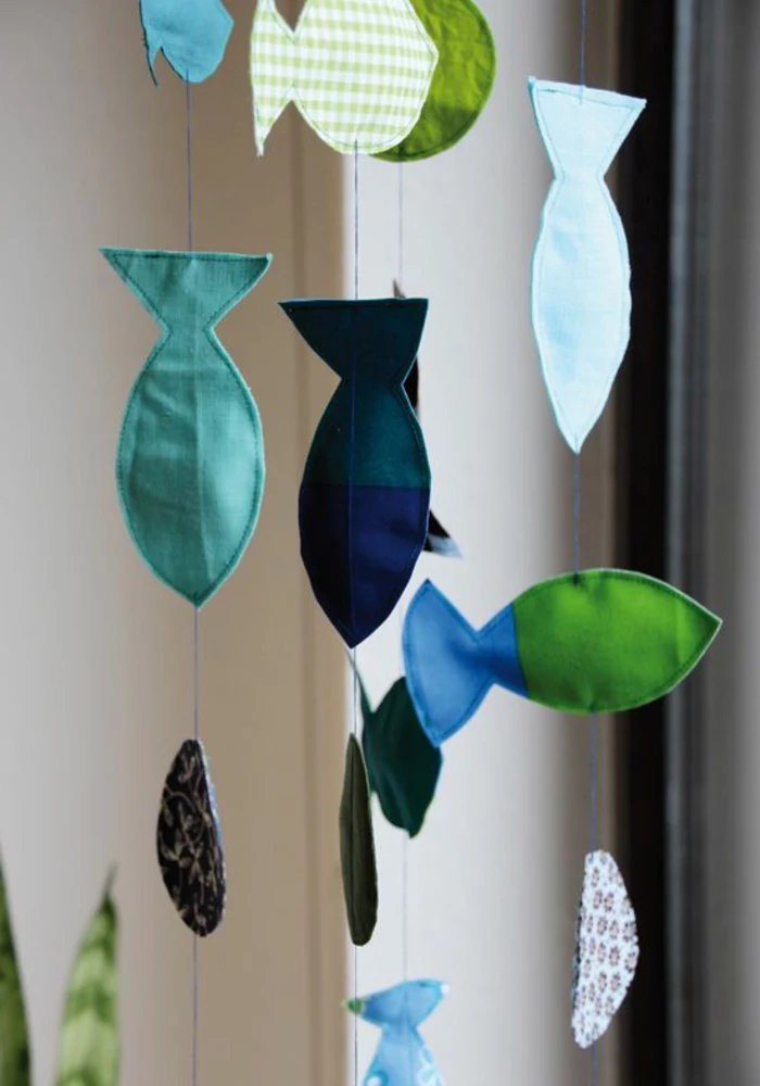 easy fun diys, four garlands made from little fabric fish, in different shades of blue and green, hanging from blue pieces of thread