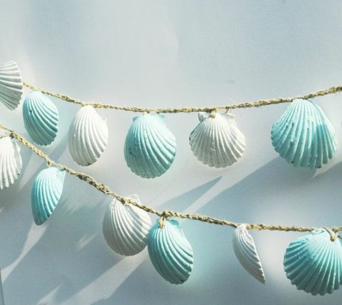 diys to do with friends, two garlands made from woven burlap thread, decorated with many seashells, painted in white and pale blue
