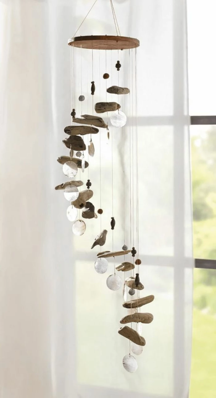 summer crafts for adults, wind chime made from small, asymmetrical pieces of driftwood, tied to a wooden circle, with string decorated with small, flat and round glass ornaments