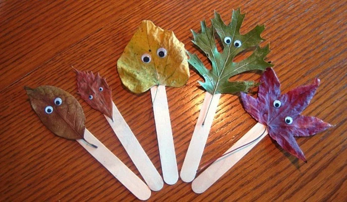cool things to make at home, five autumn leaves in different shapes and colors, decorated with stick-on eyes, stuck on ice cream sticks