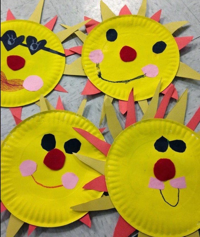 four suns made from yellow paper plates, decorated with black and red, and pink and yellow felt cutouts