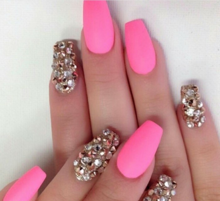 eight nails, four of which are painted hot pink, the other fore visible are entirely covered with rhinestones