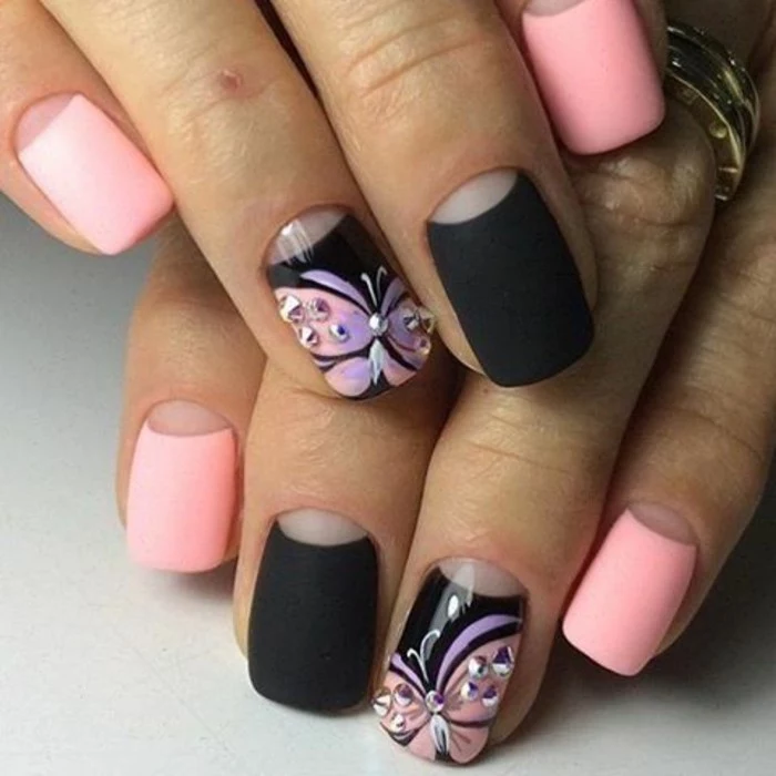 bling bling nails, two hands with nails painted in pale pink and black matte polish, ring fingers' nails painted with butterflies and decorated with rhinestones