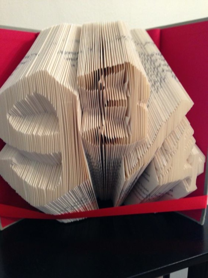 folded book art, book with hard red covers, decorated with red ribbon, and opened to display the numbers 9 3/4, made from folded pages