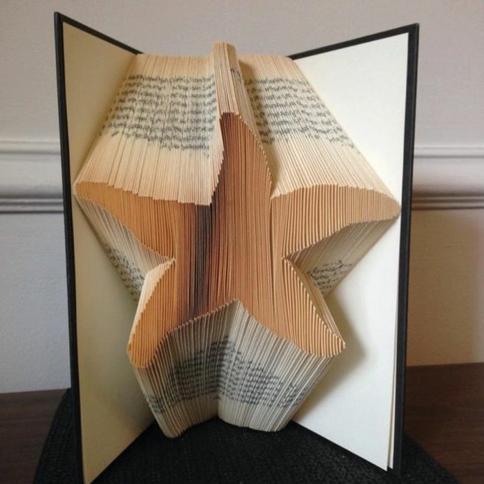 folded book art, opened book with black and white hard covers, containing starfish shape, made from folded pages