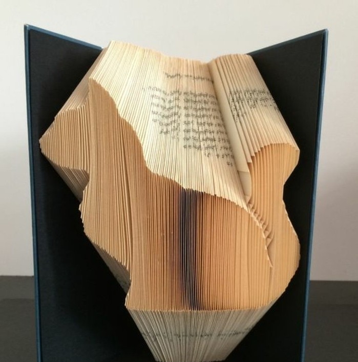 folded book art patterns, book with black hard covers, opened to display a cat shape, made from folded yellowy pages