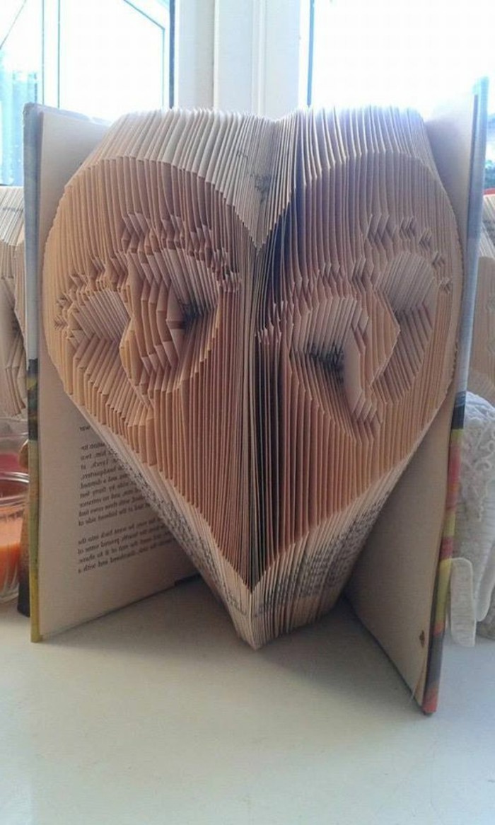 folded book art patterns, two sets of small baby foot prints, inside a heart shape, made from folded pages, inside an open book