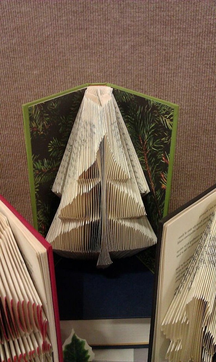 folded book art patterns, small Christmas tree, made from folded pages, inside an open book, with hard green covers, and pine tree pattern, more similar books nearby