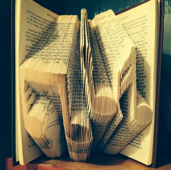 folded book art patterns, three musical notes, made from folded pages, inside an open book, with dark hard covers