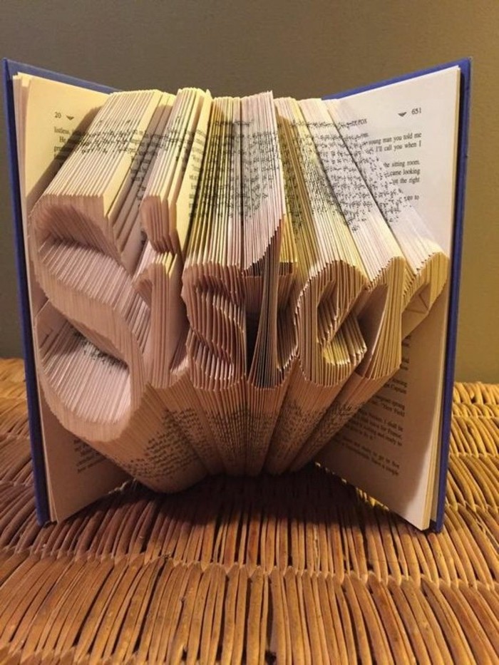 folded book art patterns, book with dark blue hard covers, opened to reveal the word sister, made from many folded pages