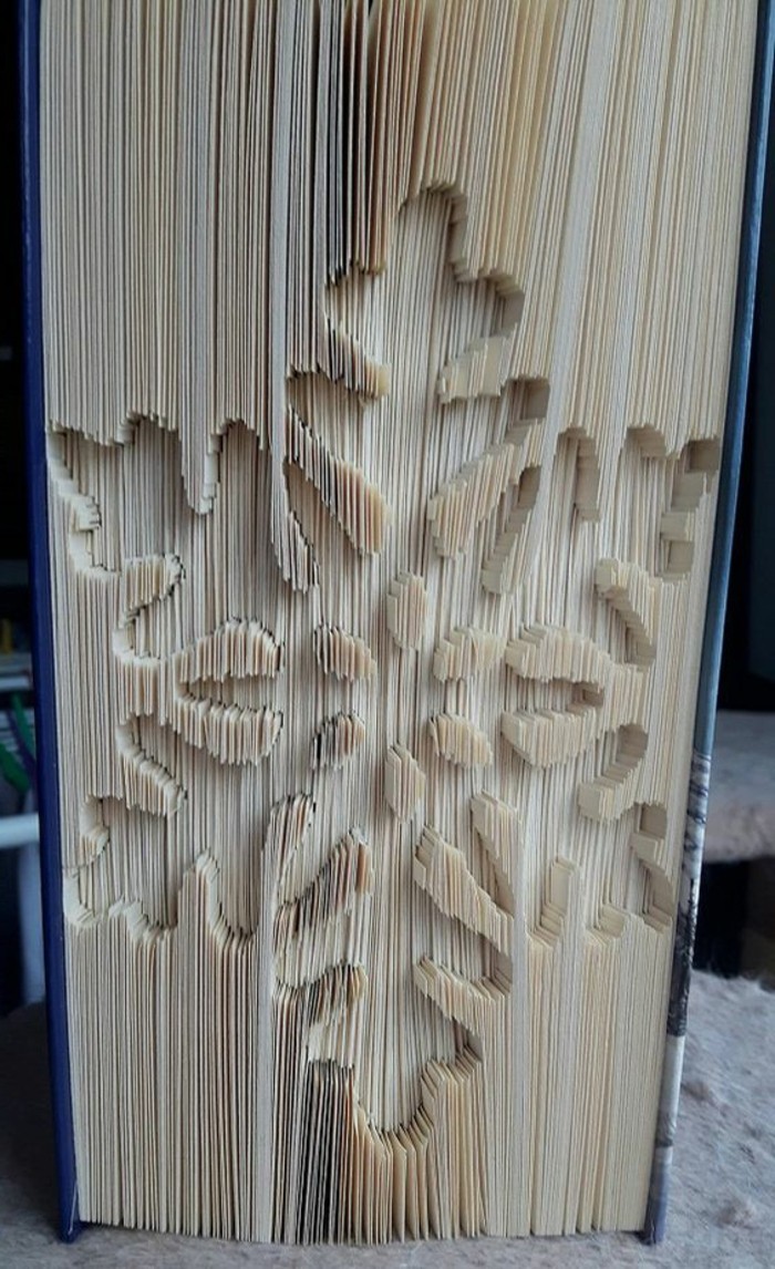 folded book art patterns, closed book with hard dark blue covers, and a snowflake shape, carved into its pages
