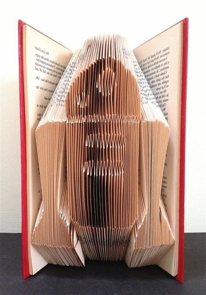 folded book art, the R2D2 robot from Star Wars, created from folded pages, inside an open book with hard red covers