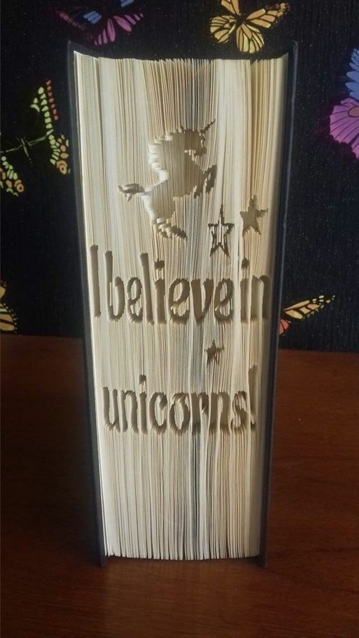 folded book art, a unicorn shape with three stars, and the sentence I believe in unicorns, carved into the pages of a closed book