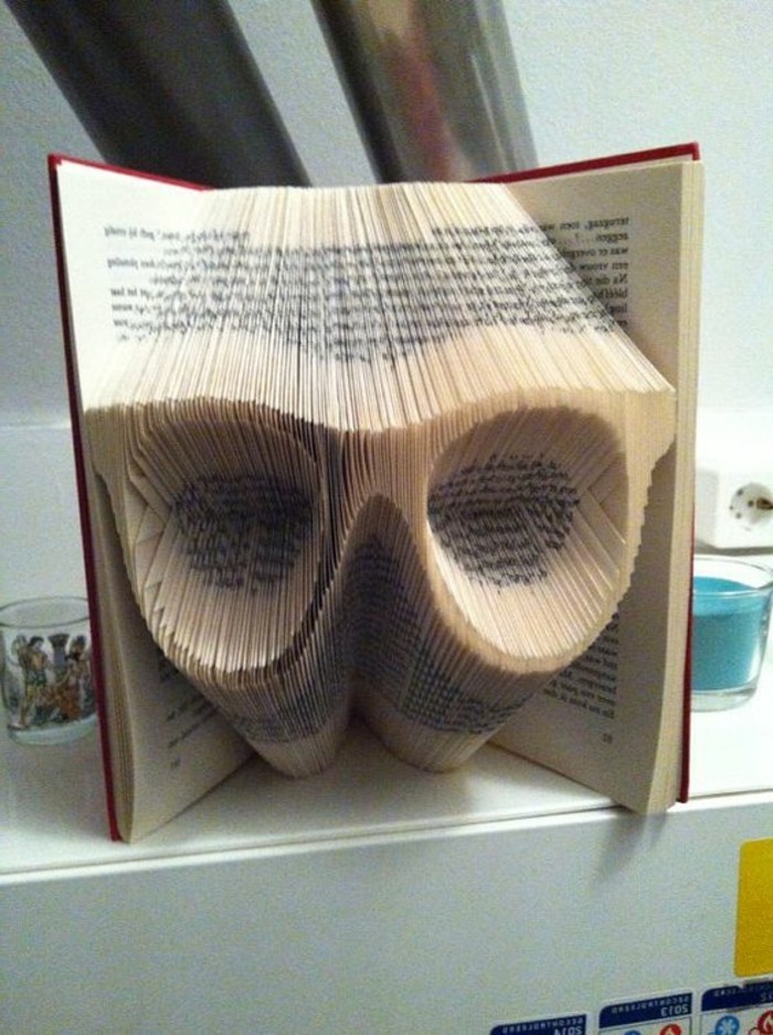 bookfolding, open book with red hard covers, containing eye glasses, made from folded pages