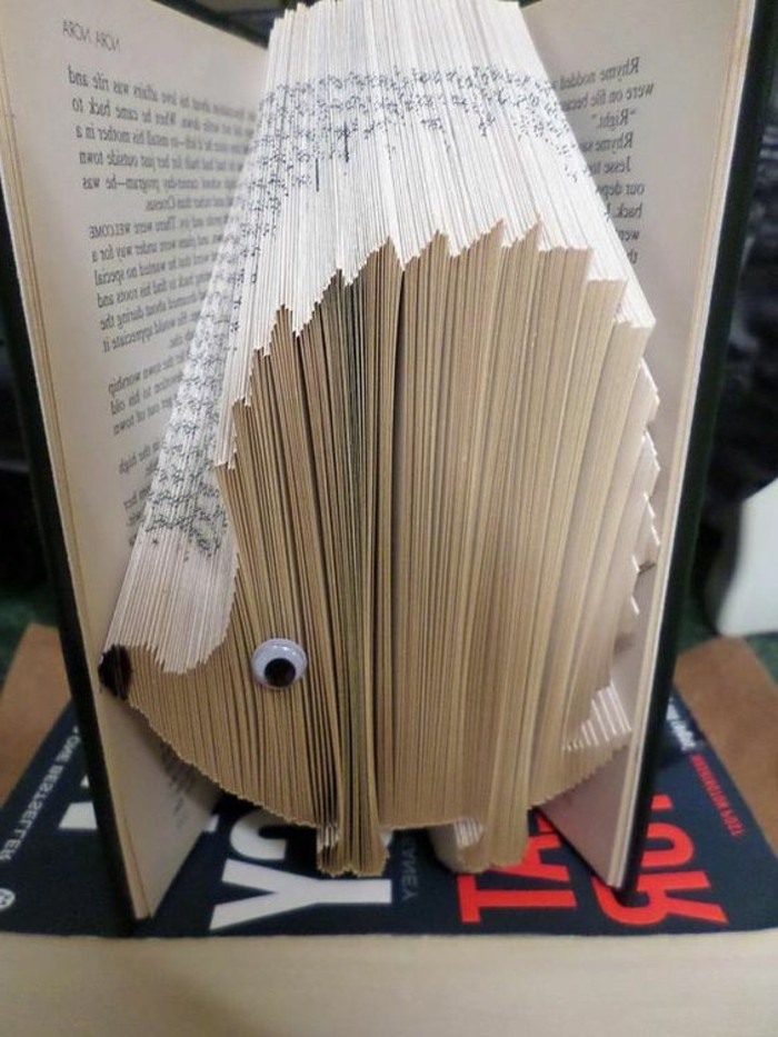 folded book patterns, book with black hard covers, opened to reveal a hedgehog shape, made from folded pages, decorated with black marker, and a stick-on googly eye