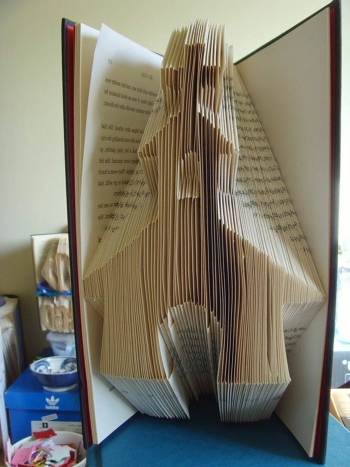 folded book patterns, a church shape, made from folded pages, inside a thin open book, with hard covers
