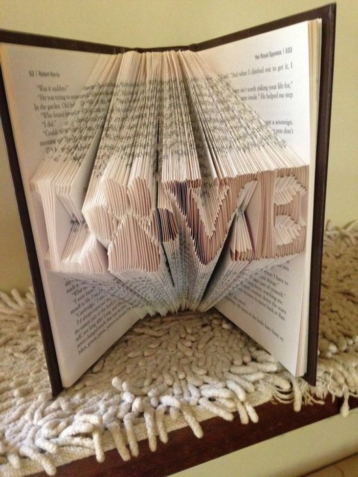 folded book patterns, the word love, with the o replaced by a paw print, made from many folded pages, inside an open book