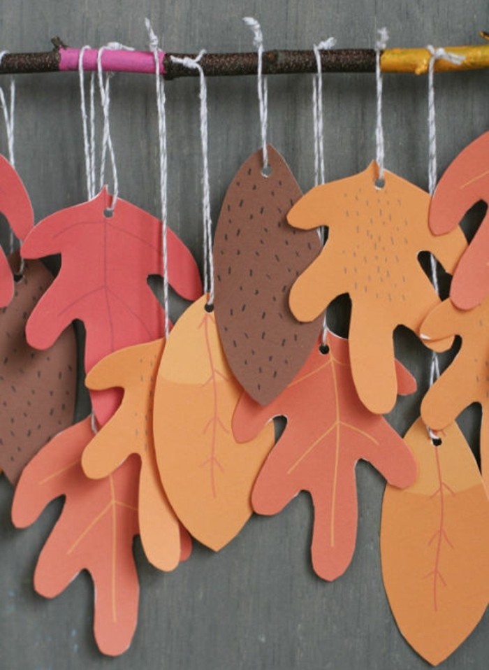 cool things to make at home, many orange and brown autumn leaves, made from paper, tied to a tree branch with white string