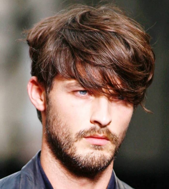 hairstyles for medium length hair, auburn haired man with long, wavy bangs partly covering his eyes, short beard and mustache