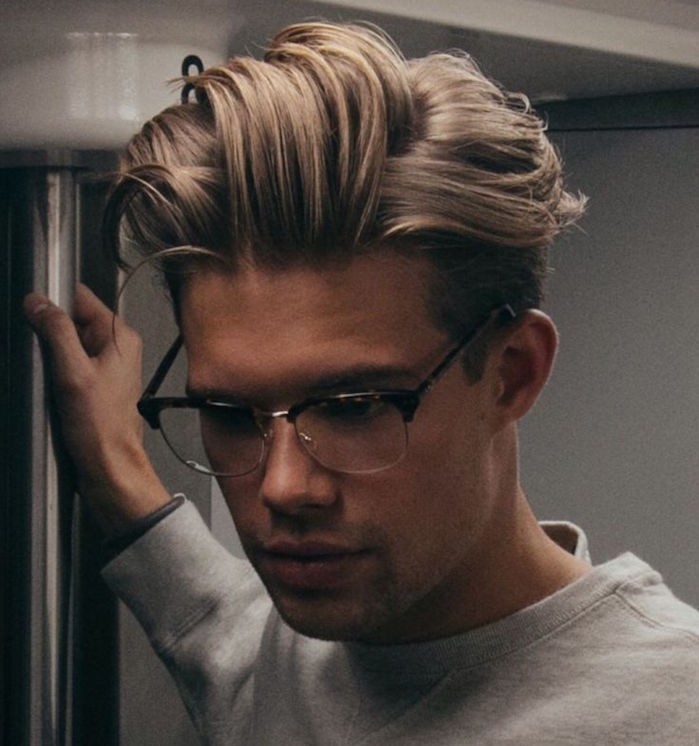 hairstyles for medium length hair, platinum blonde man with glasses, hair gelled up in messy pompadour style