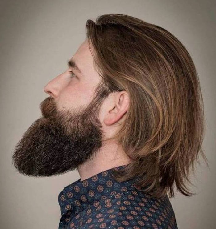 man with big beard, in profile and looking up, smooth dark blond hair tucked behind his ears, blue floral shirt