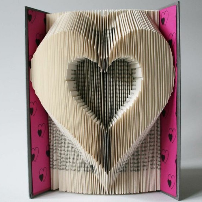 heart shape made from folded vintage pages, inside an open book, with pink and black hard covers