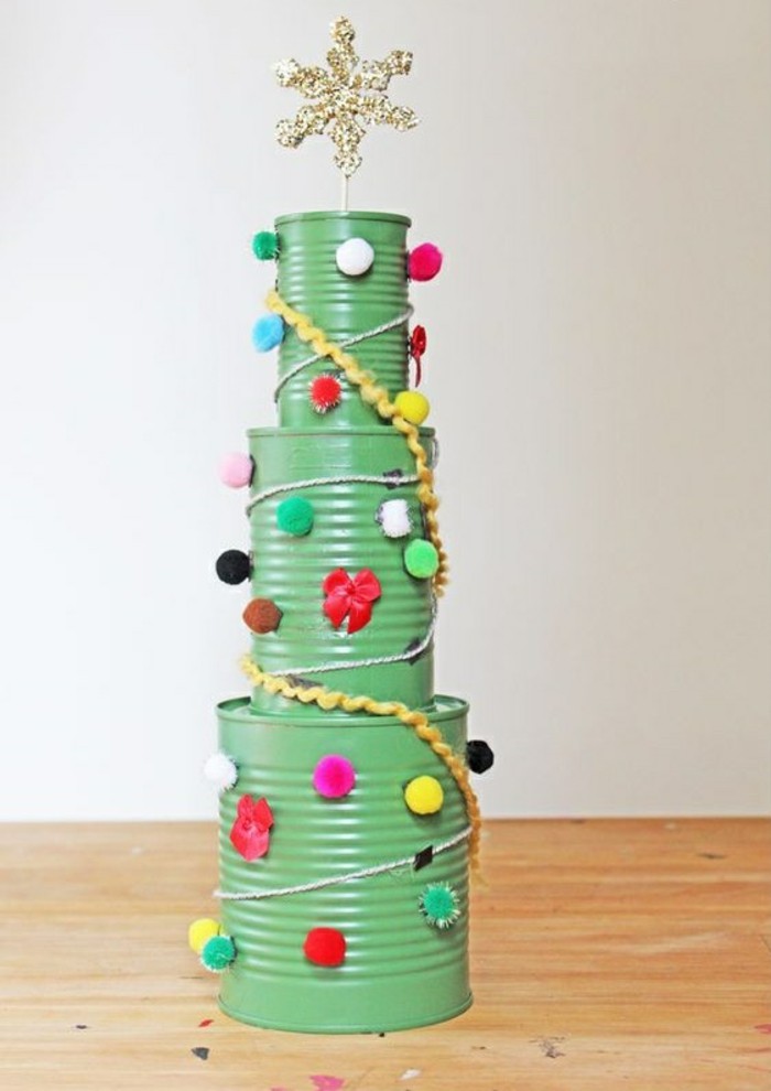 metal tin containers, christmas tree made from three differently sized cans painted in green, stacked on top of each other, decorated with colorful pom poms and tread, sparkling gold star on top