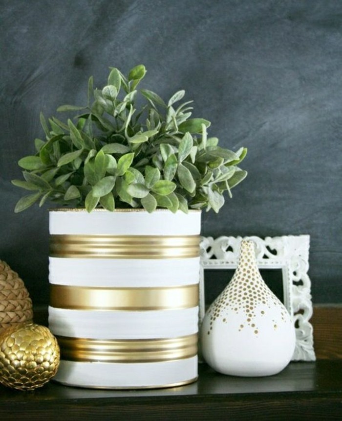 metal tin containers, a large tin colored with white and gold paint, containing green potted plant, white and gold decorations nearby