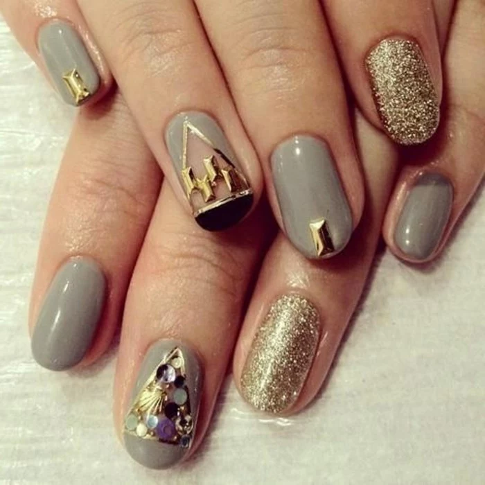 two hands with round nails, painted in grey and decorated with black gold details and/or covered in gold glitter