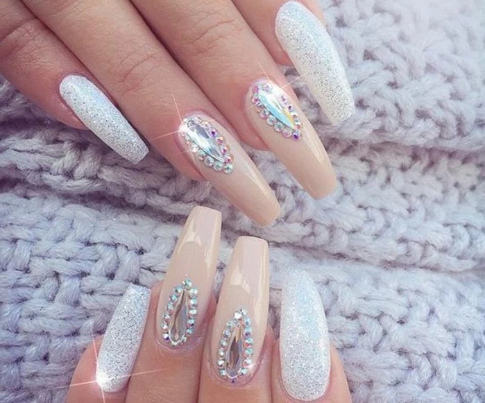 nude nails with rhinestones, eight long square nails, four with white polish and glitter, four with nude polish and rhinestones