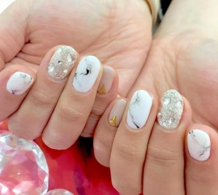 rhinestone nail art, two hands with differently colored nails, white and grey marble effect, pink with gold detail, glittering silver color with rhinestones