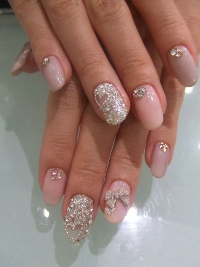 nail designs with rhinestones, round nails painted with pale pink polish, decorated with rhinestones on every finger, ring fingers' nails are entirely covered with rhinestones, and have a heart detail