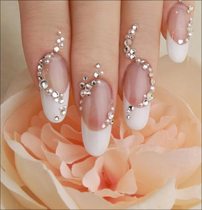 french manicure with long white tips, both nails and finger tips decorated with rhinestones
