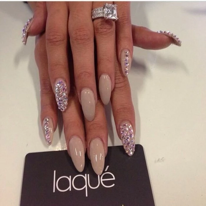 nude nails with rhinestones, long round nails with nude polish, index pinkie and thumb nails decorated with rhinestones