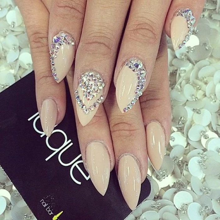 nude nails with rhinestones, sharp manicure in nude tones, decorated with many rhinestones on one hand and plain on the other