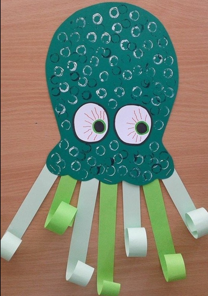 fun art projects, octopus made from dark green paper, decorated with pale green and blue paper tentacles, scales drawn in shiny marker