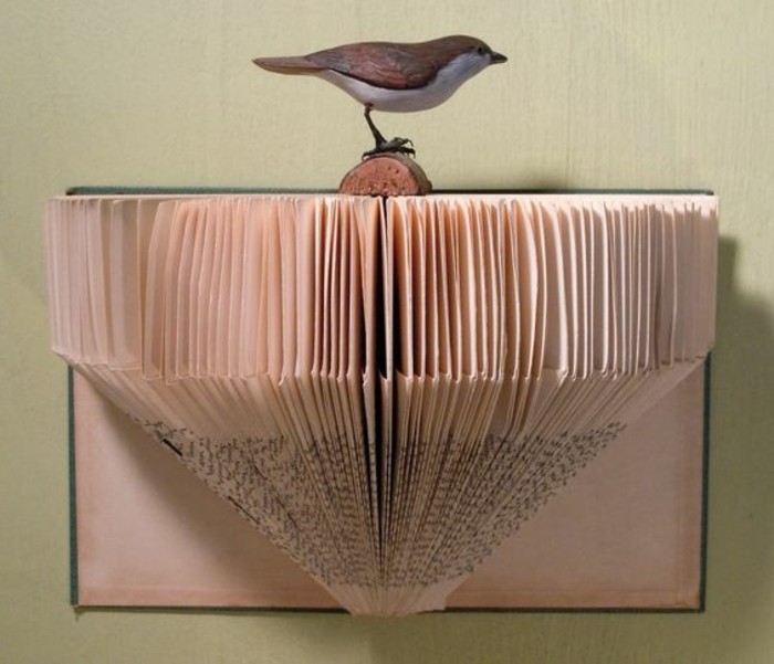 paper art, created from cut and folded vintage book pages, stuck to one of the book's covers, decorated with realistic bird ornament