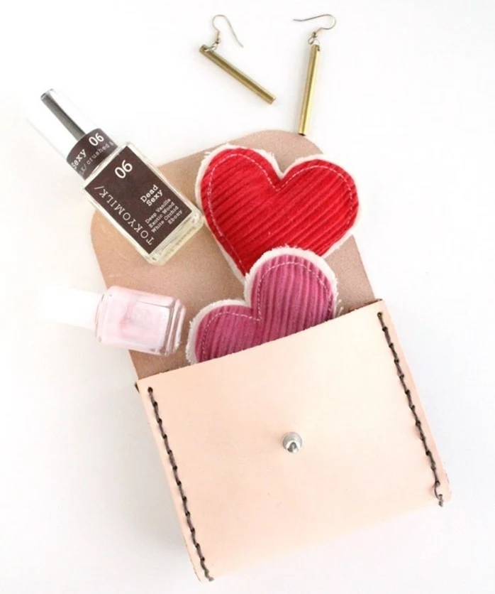 what to get your best friend for her birthday, small open hand-stitched cream leather purse, heart ornaments, nail polish bottles and earrings pouring out