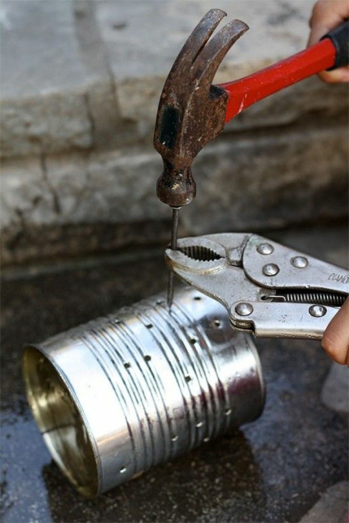 aluminum tins, person making holes into an aluminium can, using a nail, held with pliers, and a hammer