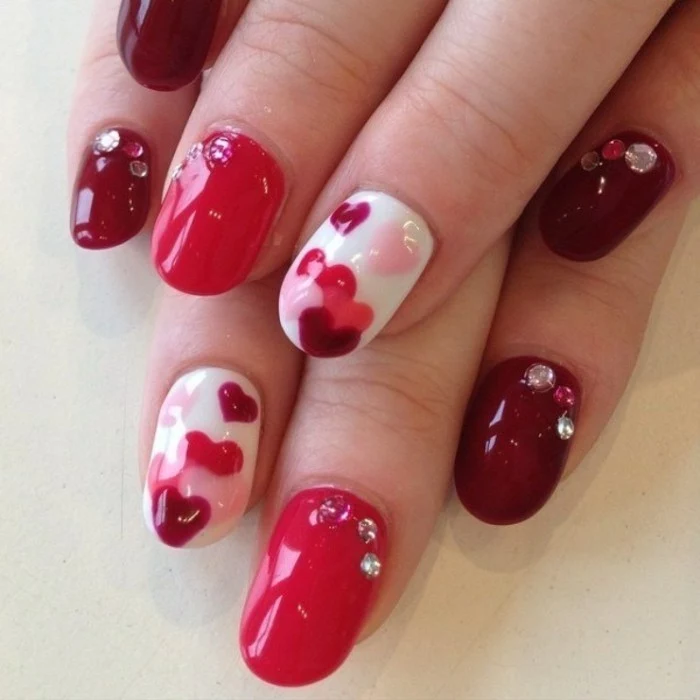 wine red, dark hot pink and white nail polish, decorated with rhinestones and painted hearts